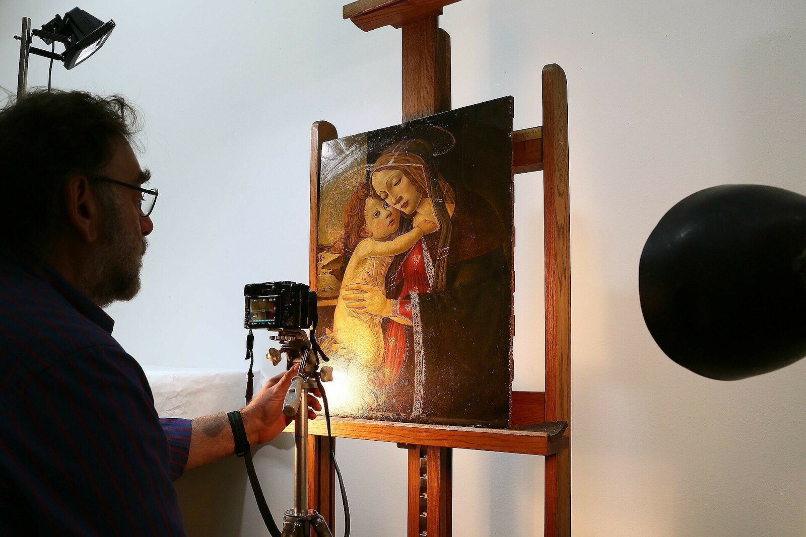 Un restaurateur examine un tableau ancien sous une lumière rasante, au Palais des Beaux-Arts de Lille